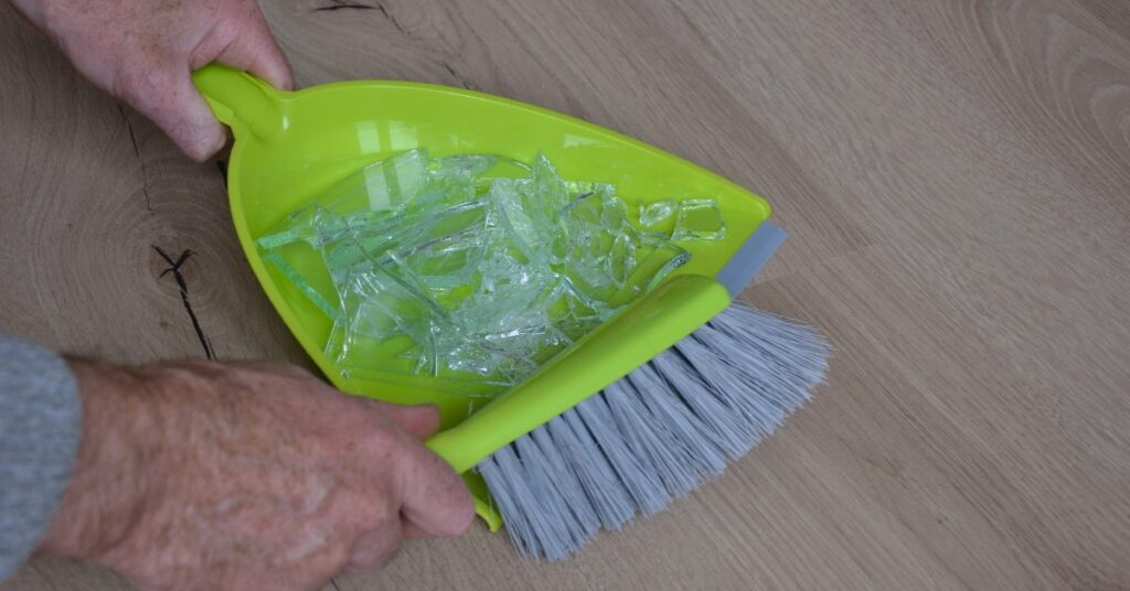 Use a dustpan and broom to carefully sweep the bigger pieces.